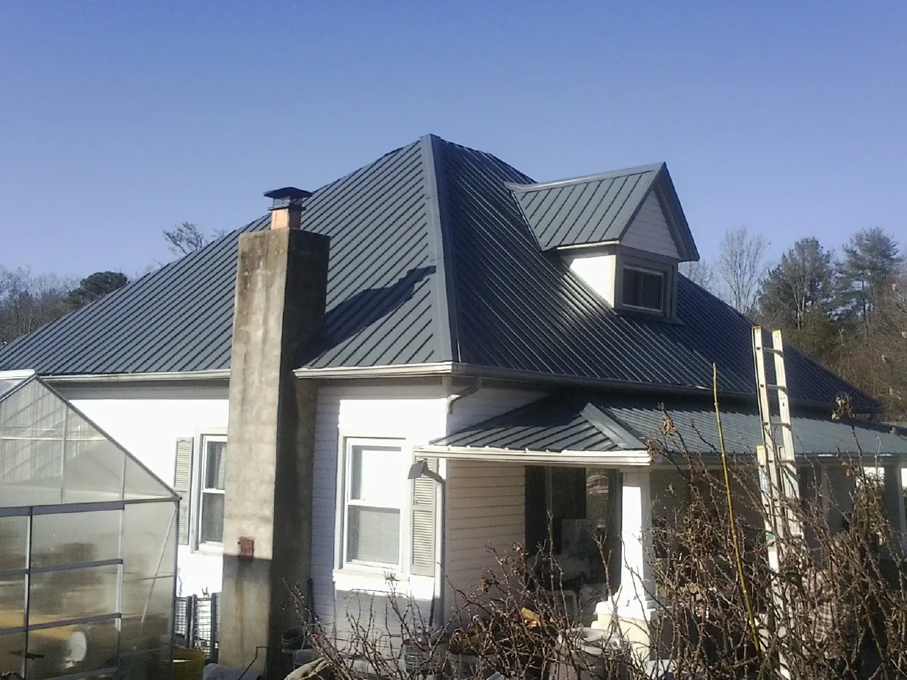 Dark blue standing seam metal roof on a white farmhouse with dormer — Slate & Tile Roof Repair by Roofing Brothers in Mifflin