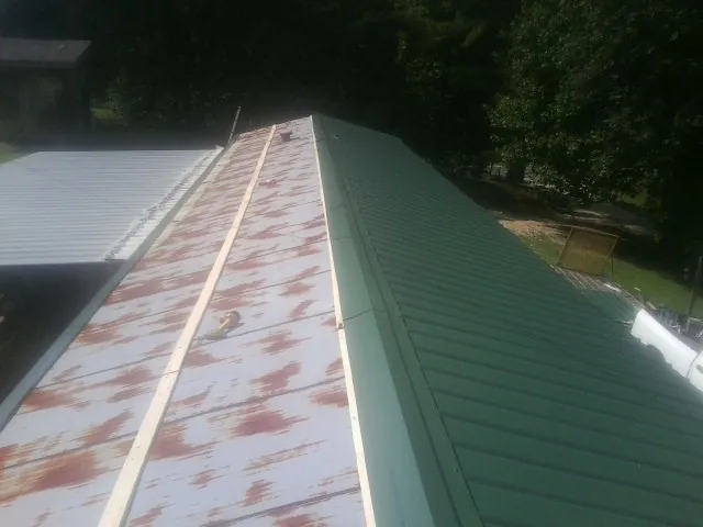 Old rusted panels beside newly installed green metal roofing — Wind Damage Roof Repair by Roofing Brothers in Mifflin