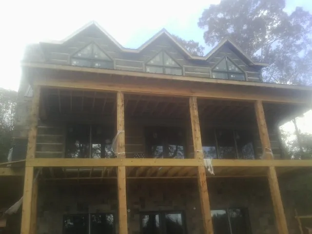 Dormers and porch framing on a large log home under construction — Roof Coating work by our crew in Mifflin