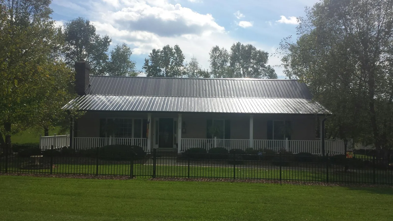 Gray metal roof on a brick ranch with a full width front porch — Gutter Guard Installation work by our crew in Mifflin