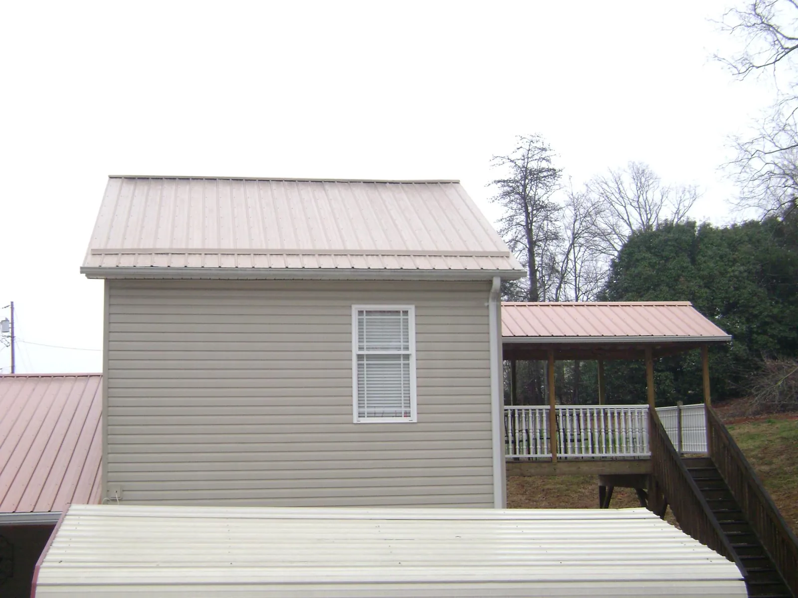 Tan metal roofs on a two story addition and attached porch, from a Roof Replacement job in Mifflin
